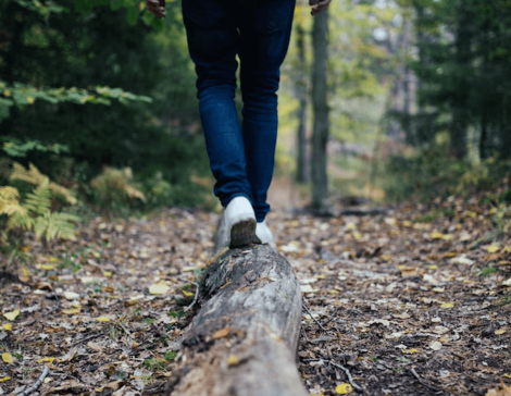 Person walking carefully along a forest log representing personal growth